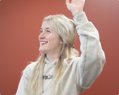 Girl sitting in class with raised hand